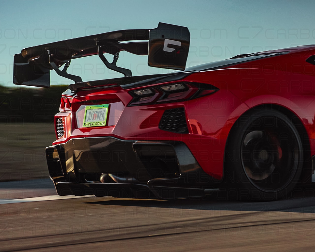 Close-up of the rear of a red Corvette C8 featuring a mounted rear spoiler.