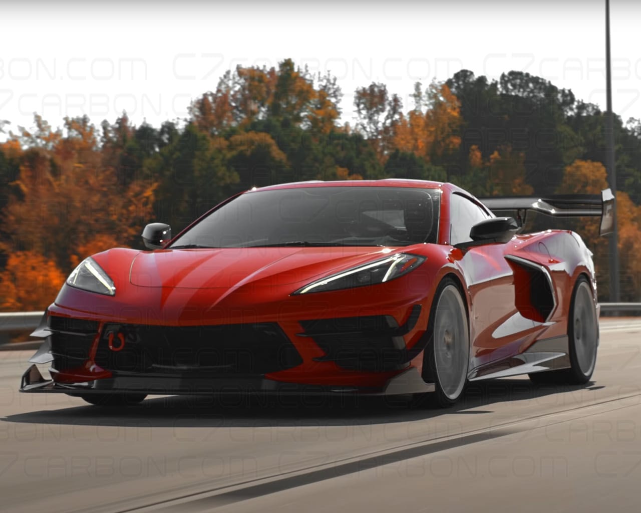Red Corvette C8 on a racetrack, with a mounted rear spoiler for added downforce.